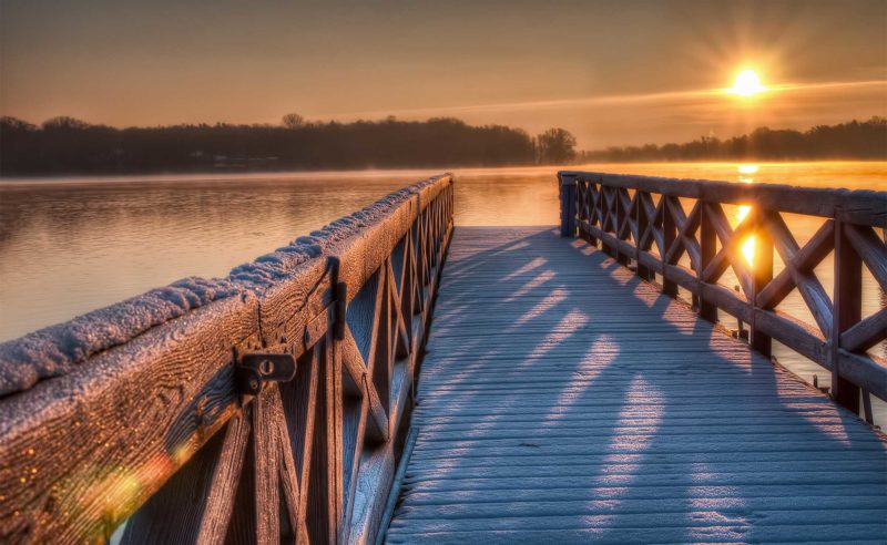 Schneebedeckter hölzerner Steg am Ruppiner See bei der Abendsonne