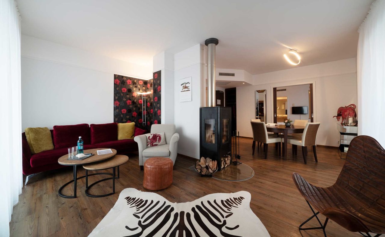 Wohnzimmer mit Kamin und Esstisch in der Suite des Hotel Neuruppin
