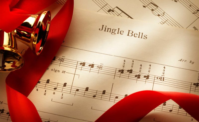 Notenblatt für das Lied Jingle Bells mit roter Schleife und goldenem Glöckchen