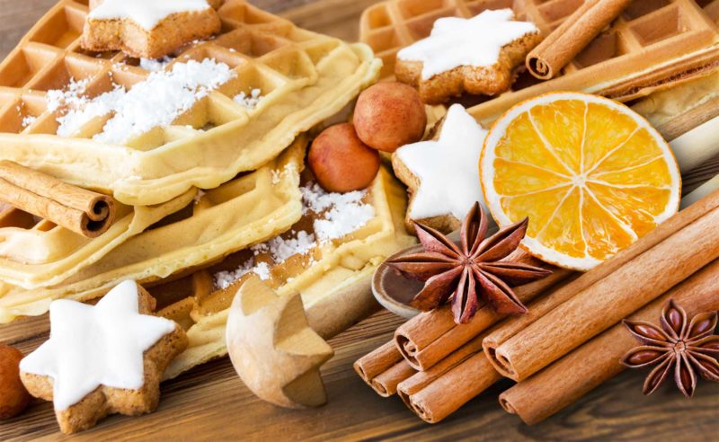 Weihnachtlich angerichtete Waffeln, Zimtsterne, Orangen, Nüsse und Anissterne