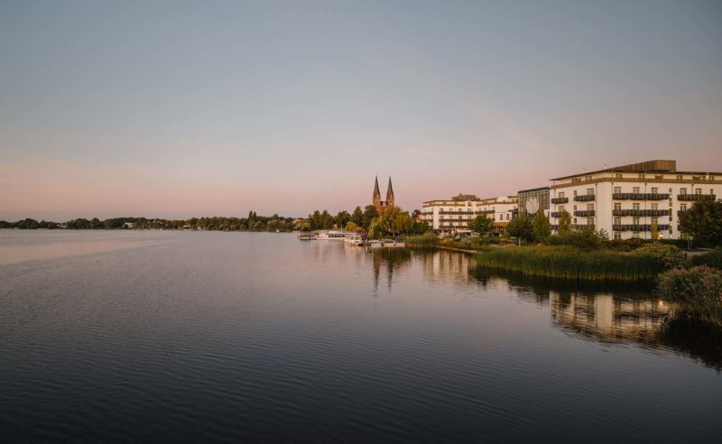 Außenaufnahme des Resort Mark Brandenburg aus See Perspektive mit Neuruppin im Hintergrund
