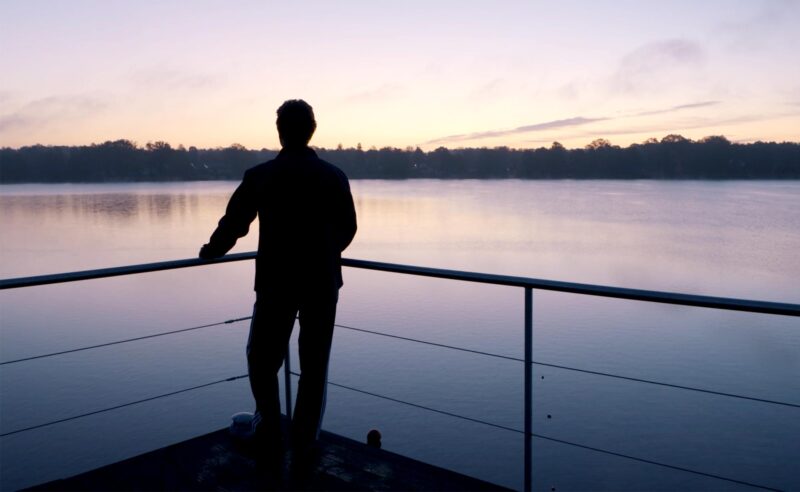 Eine Person genießt die Aussicht über den Ruppiner See im Abendlicht.