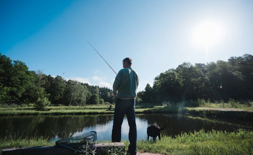 Partner Fischzucht von hinten beim Angeln mit seinem Hund