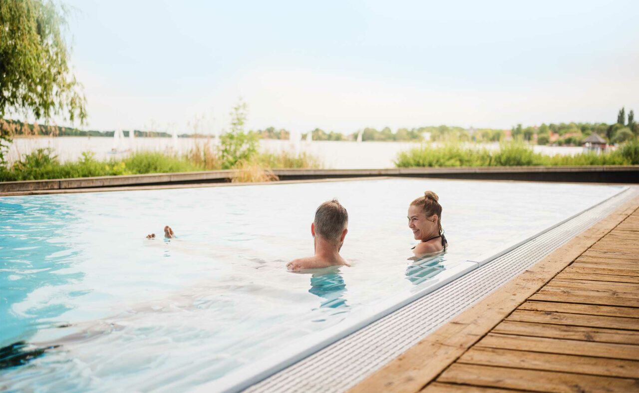 Paar badet in einem Außenpool der Fontane Therme mit traumhaftem Blick über den Ruppiner See