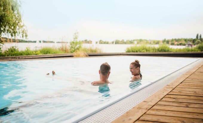 Paar badet in einem Außenpool der Fontane Therme mit traumhaftem Blick über den Ruppiner See