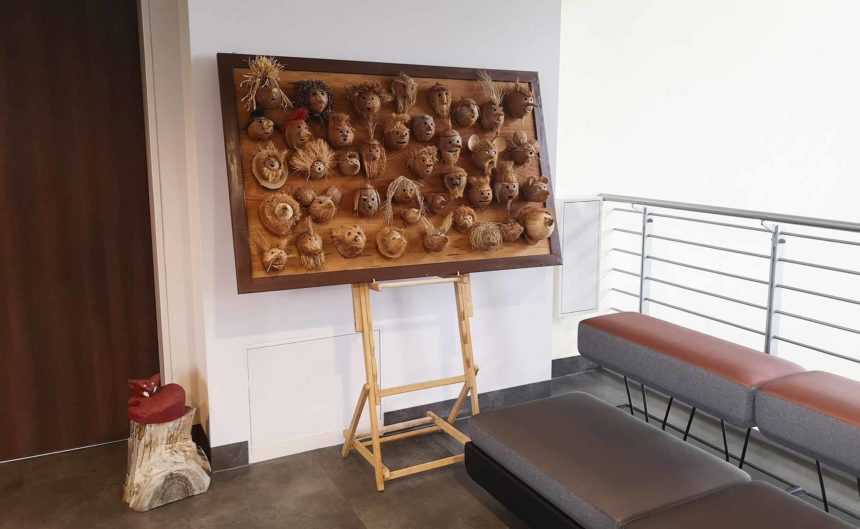 Viele selbstgebastelte Köpfe auf einem Holzbrett in der Ausstellung Andreas Posch