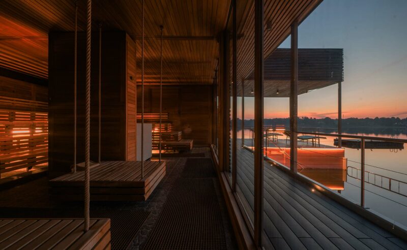 Ein Sauna mit Holzliegen im Abendlicht und Blick auf den See.
