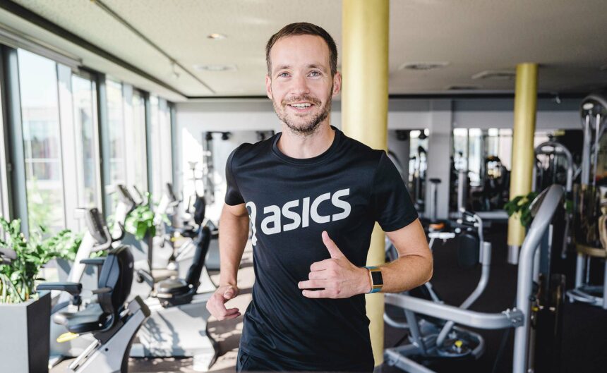Nahaufnahme eines joggenden Fitnesstrainers in einem hellen Sportraum.
