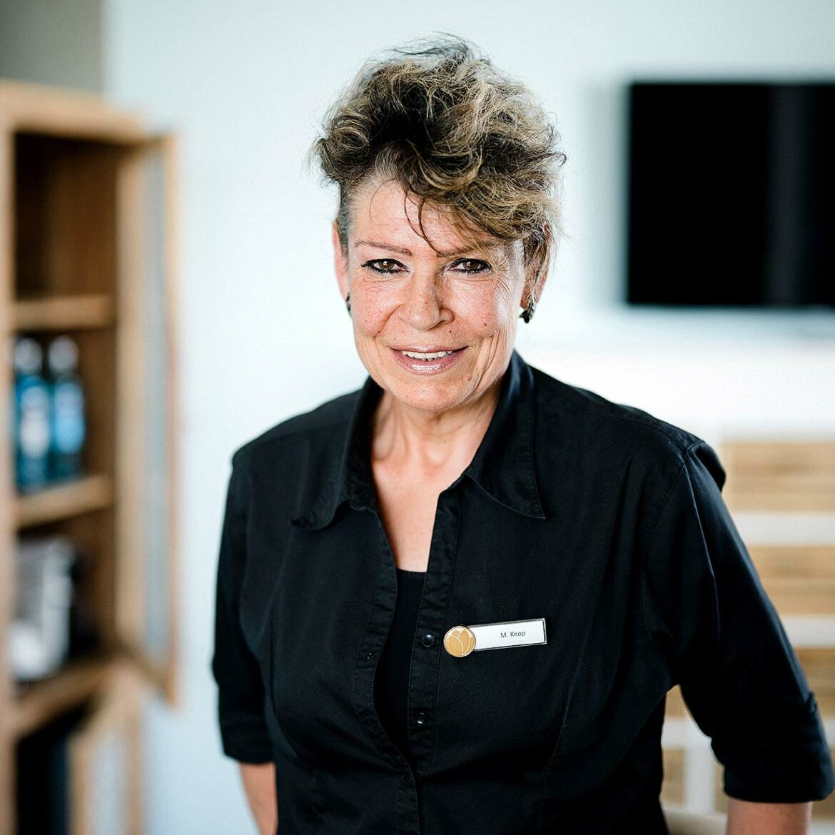Nahaufnahme einer lächelnden Housekeeping Mitarbeiterin mit schwarzer Arbeitskleidung.
