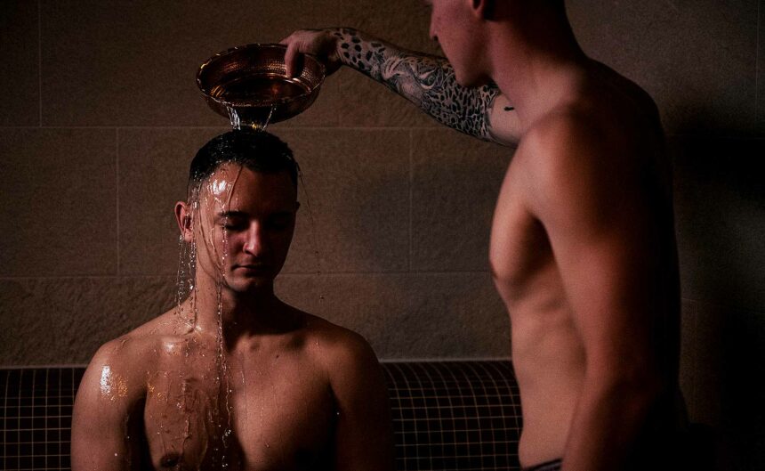 Mann übergießt einen anderen Mann mit Wasser