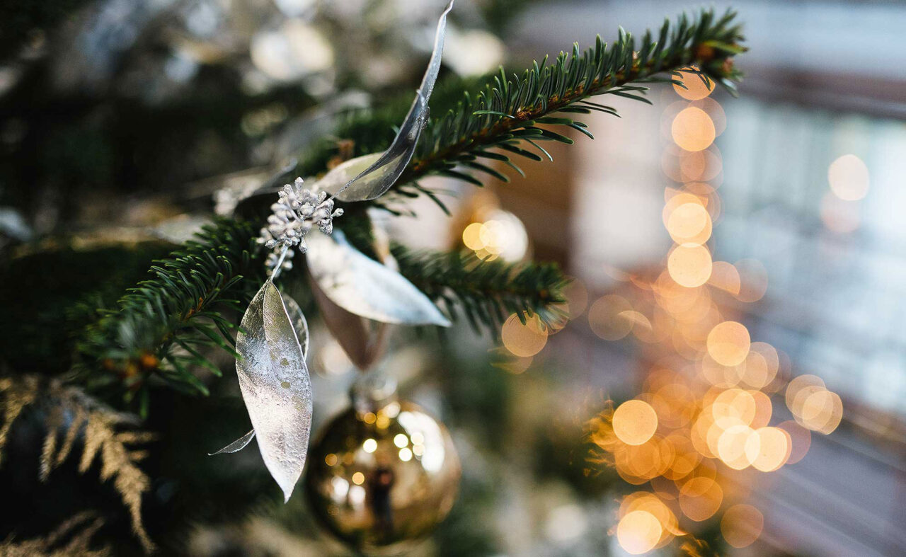 Tannenzweig mit Kugeln und Lichtern im Hintergrund
