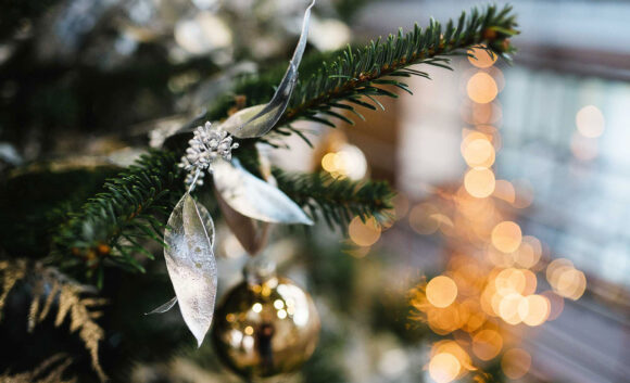 Tannenzweig mit Kugeln und Lichtern im Hintergrund