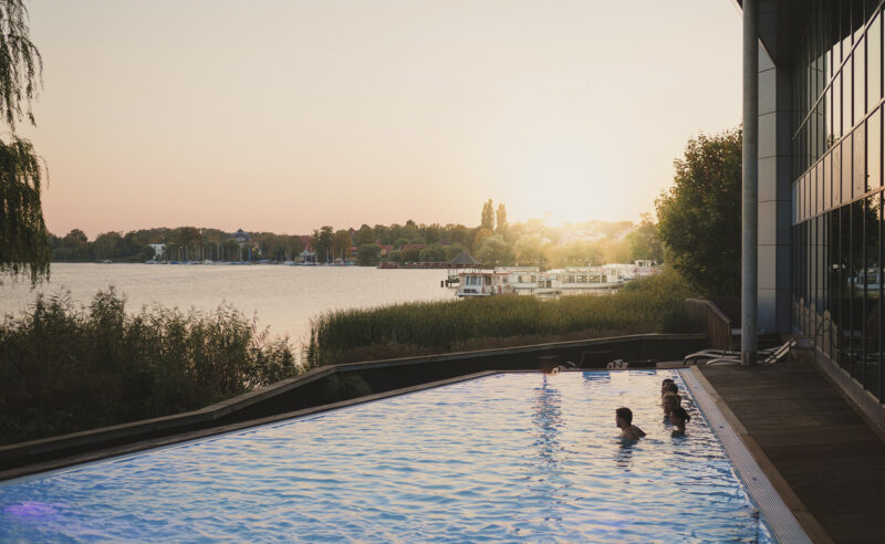 Außenpool der Fontane-Therme mit Blick auf den Ruppiner See im Sonnenuntergang