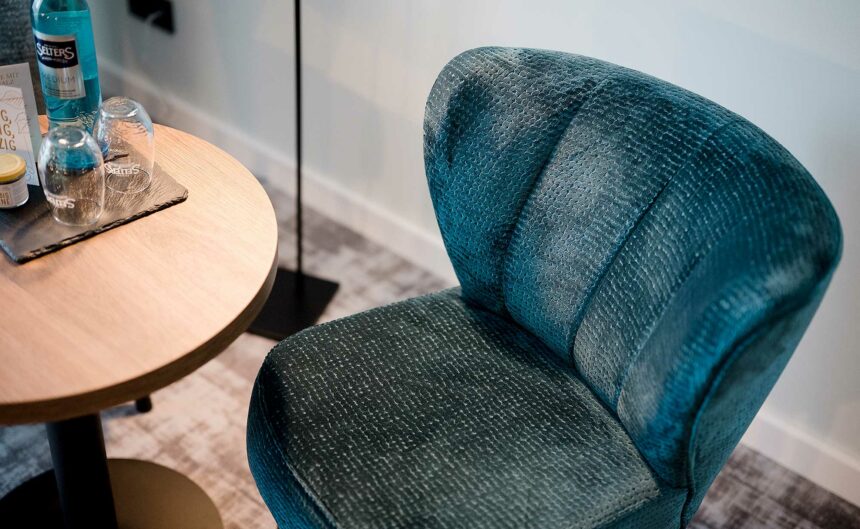 Nahaufnahme von oben auf einen blauen Sessel neben einem Beistelltisch.