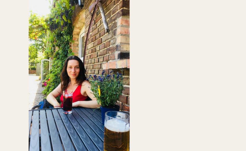 Frau genießt eine Johannisbeerschorle bei schönem Wetter im Biergarten