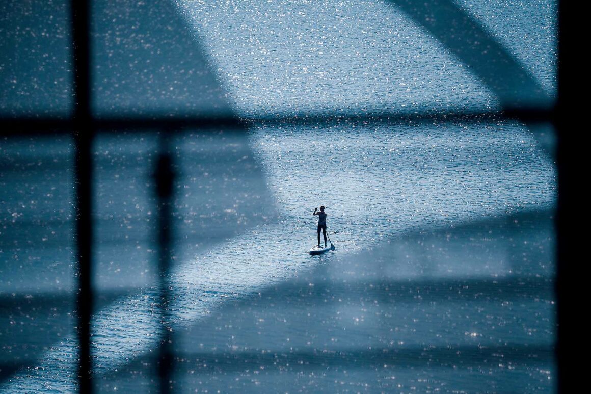 Eine Person ist auf dem Ruppiner See mit einem Stand-Up Paddle zu sehen.