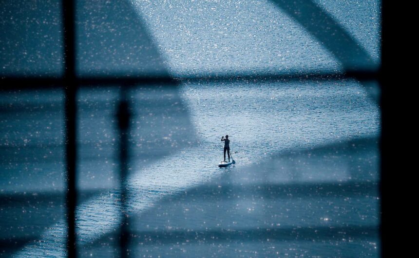 Eine Person ist auf dem Ruppiner See mit einem Stand-Up Paddle zu sehen.