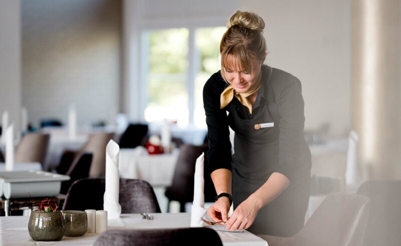 Eine Servicemitarbeiterin des Resort Mark Brandenburg bereitet einen Tisch für die Restaurantgäste vor.